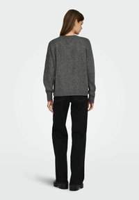 Suéter gris de punto con cuello redondo, hombros caídos, dobladillo acanalado y superficie texturizada, combinado con pantalones negros de pierna recta.