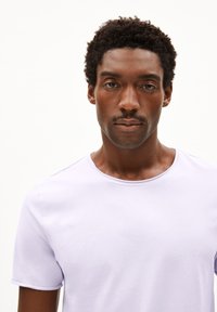 Lichtpaarse, T-shirt met korte mouwen en een ronde hals, gemaakt van zachte stof; gladde textuur en eenvoudig ontwerp zonder patronen of accenten.