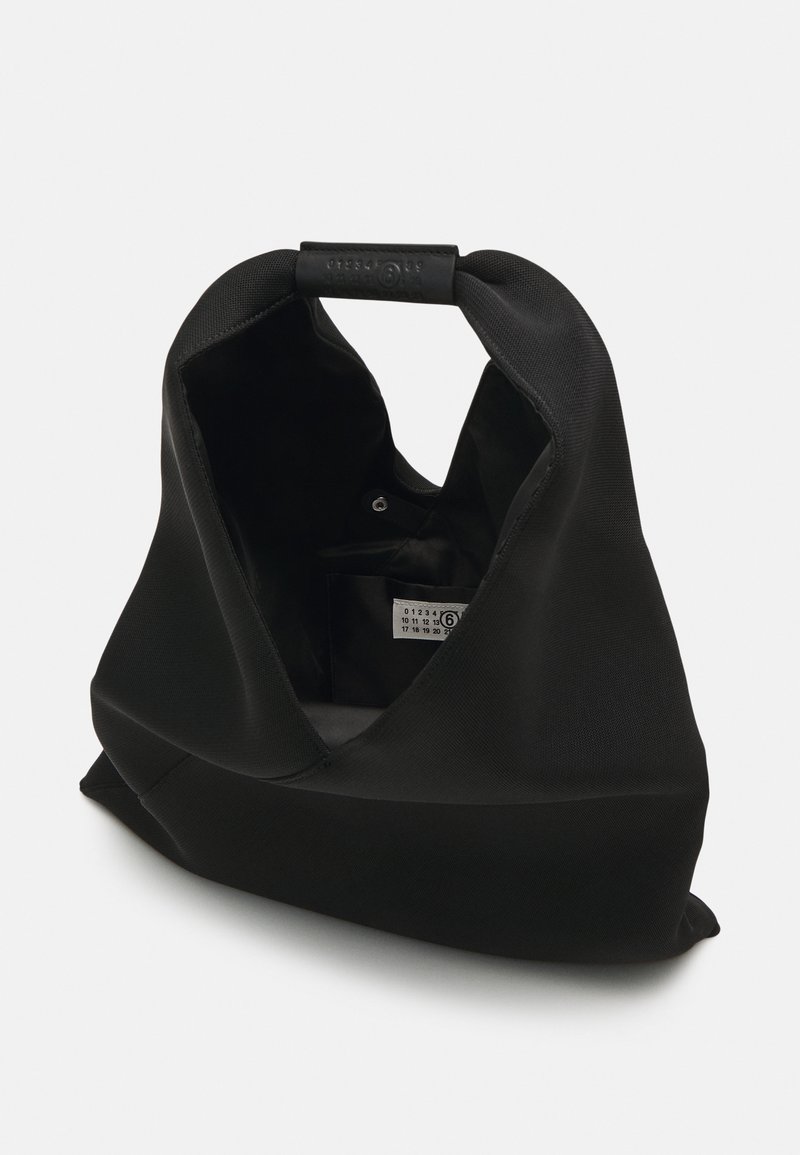 Bolsa de tela negra con un diseño relajado, abertura amplia y un cierre en forma de V distintivo. El interior presenta una etiqueta y un hardware mínimo.