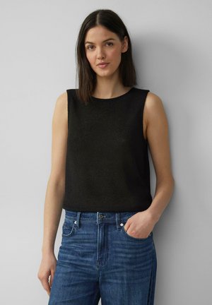 Zwart mouwloos topje van een gestructureerd materiaal, gecombineerd met hoog-waisted blauwe jeans, die een minimalistisch ontwerp en schone lijnen tonen.