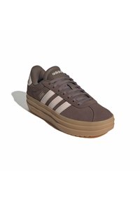 Dark gray Adidas sneaker with beige sole and three white stripes, viewed from front right angle on white background.