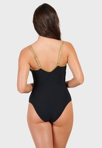 Svart baddräkt i ett stycke med gulddekorativa remmar, med en V-formad ryggdesign och en slät tygstruktur.