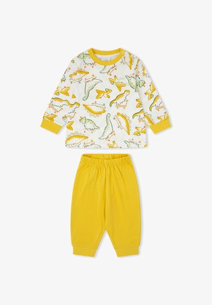 Camiseta blanca de manga larga para niño pequeño con puños amarillos y dinosaurios sobre patinetes, combinada con pantalones amarillos lisos con cintura elástica.