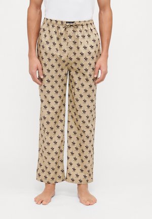 Beige Schlafanzughose mit schwarzem Hundefilm-Muster, elastischer Bund mit Kordelzug, lockere Passform und weichem Stoff.
