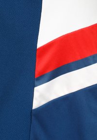 Tessuto sportivo blu navy con texture a rete, caratterizzato da un design diagonale a strisce rosse e bianche, affiancato da accenti blu scuro e azzurro.