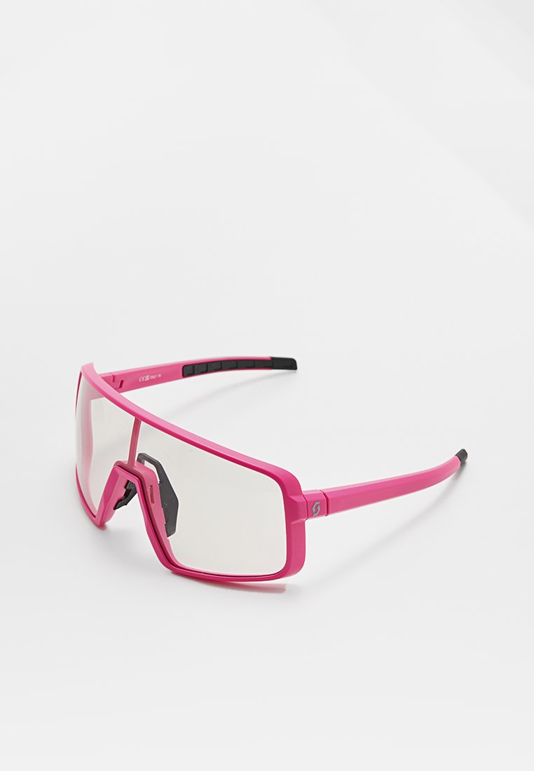 Gafas de sol deportivas rosas con montura rectangular, lentes claros y acentos texturizados en negro en las patillas. Material plástico ligero.
