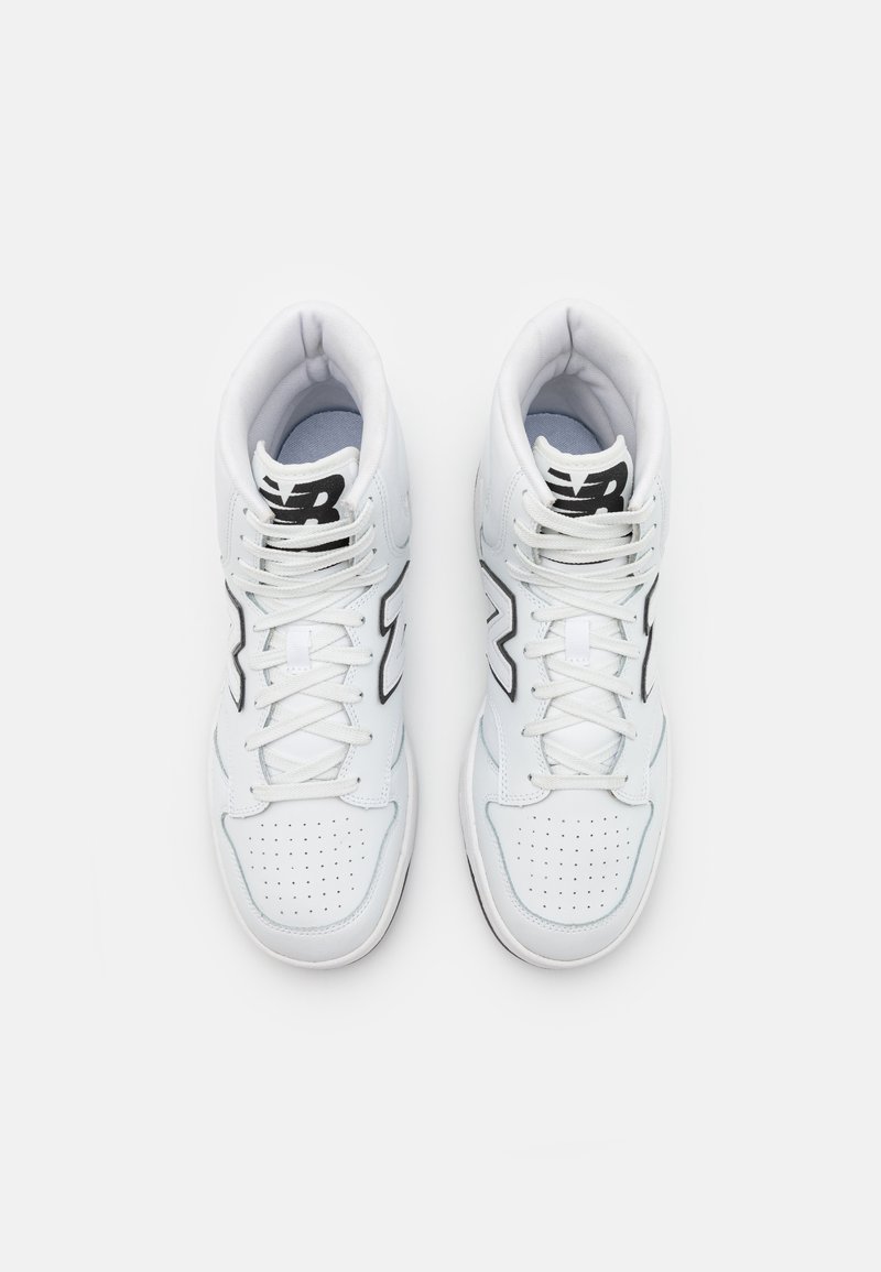 Scarpe sportive bianche alte con dettagli perforati, accenti del logo neri e suola texturizzata. I lacci sono infilati attraverso gli occhielli per una vestibilità sicura.