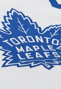 Maglia da hockey bianca con il testo ricamato blu "TORONTO MAPLE LEAFS" e un grande logo a foglia d'acero blu, dettagliato con fine cucitura.