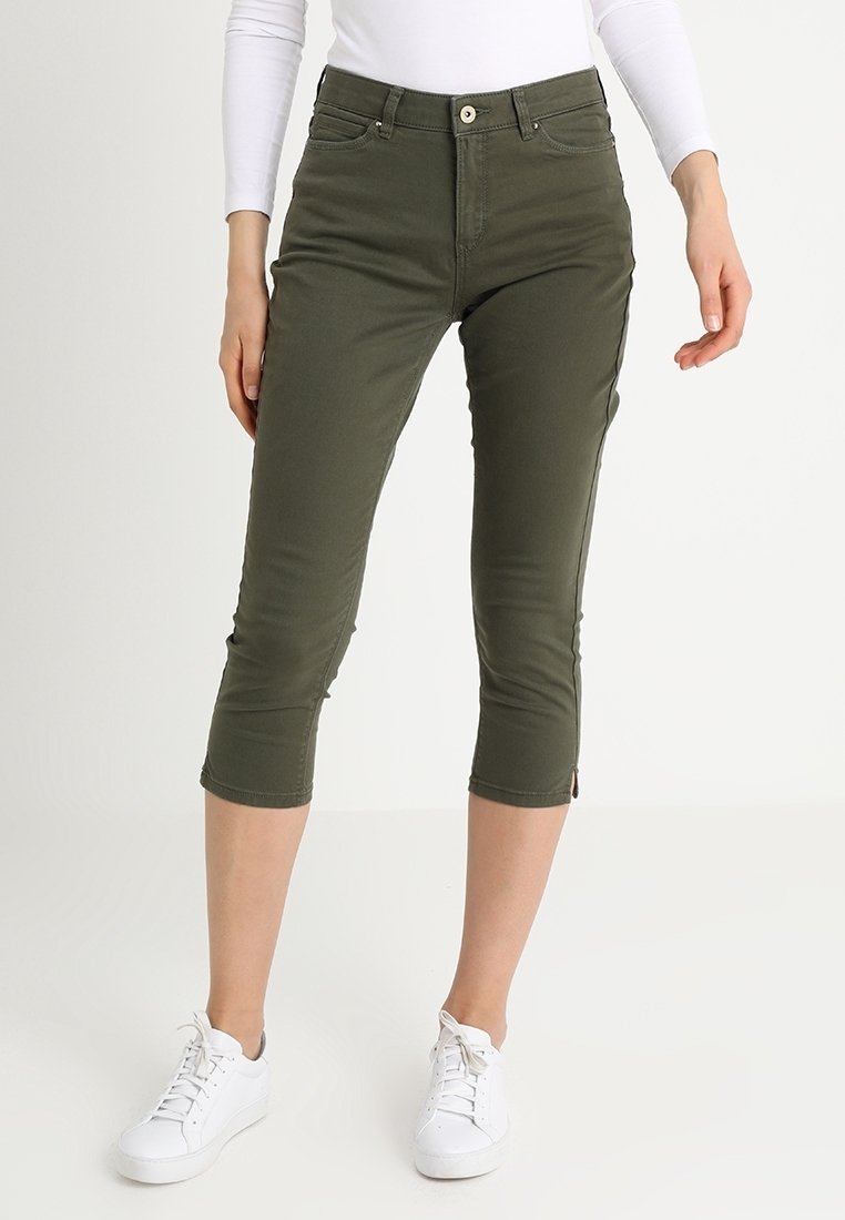 Pantalones capri verde oliva hechos de denim con un ajuste ceñido, que cuentan con bolsillos frontales, cierre de cremallera y cremalleras en los tobillos para ajuste.