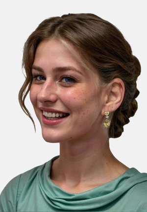 Orecchini in gemma gialla con forme a cuore e goccia, incastonati in argento, indossati da una persona con un top turchese chiaro e capelli acconciati.