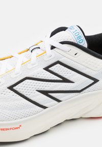 Bijela New Balance tenisica za trčanje s crnim logotipom, bijelim vezicama, žutim akcentima i "Fresh Foam X" amortizacijom na potplatu.