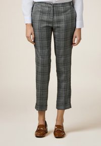 Rutiga byxor i svart och vitt, skräddarsydd passform, kort längd, med en jämn struktur och knappstängning, matchade med bruna loafers.