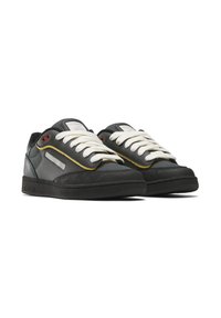 Black and gray sneakers with white laces, suede and leather materials, rounded toe, yellow accent line, and textured rubber sole.