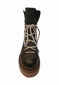 Botín de cuero marrón grueso con caña negra acolchada, que presenta cordones de cuerda beige y una suela gruesa y texturizada. Diseño de punta redonda.