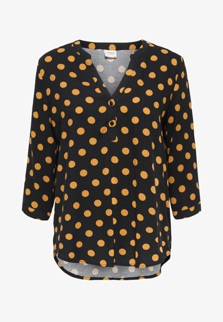 Blouse noire à manches longues avec de grands pois jaune moutarde, col en V avec deux boutons et ourlet arrondi.