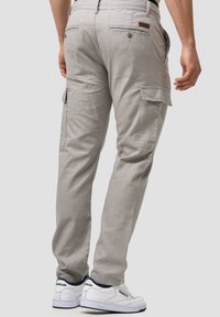 Graue Cargo-Hosen mit Seitentaschen und Knopfverschluss. Hergestellt aus leichtem Stoff, mit lockerer Passform und schlichten Steppnähten.