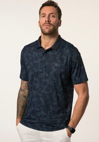 Námořnickomodrá polo košile z lehkého materiálu, která má jemný abstraktní vzor, krátké rukávy a límeček.