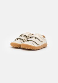 Beżowe buty dziecięce z dwoma rzepami, gumową podeszwą i teksturowanym wykończeniem. Miękki materiał o zaokrąglonym kształcie i minimalistycznym designie.