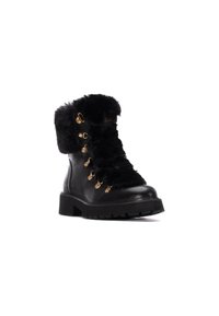 Botas de senderismo de cuero negro con un collar de pelaje, accesorios dorados y una suela texturizada. Cuentan con un sistema de cordones para un ajuste seguro, ideales para el clima frío.