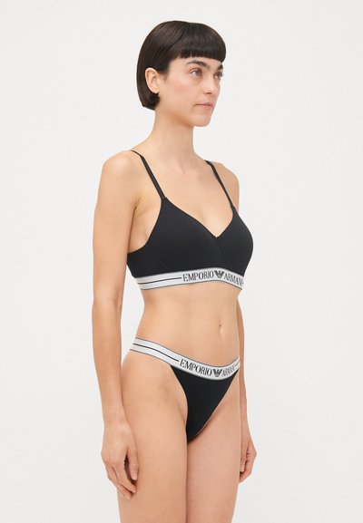 Black lingerie set featuring a bralette with adjustable straps and a wide elastic band, paired with a matching thong with logo detailing.