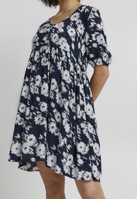Tmavě modré šaty s květinovým potiskem, krátkými nabíranými rukávy, knoflíkovým zapínáním vpředu a rozšířenou siluetou z lehkého materiálu s texturovaným vzorem.