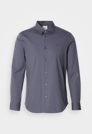 Long-sleeve button-up shirt in dark gray fabric. Features a classic collar, front buttons, and subtle logo on the chest. Smooth texture.