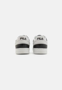 Fila sneakers with a white and black color scheme, leather material, flat sole, padded collar, and prominent logo on the back.