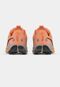 Pantofi sport ușori de culoare portocalie, cu un superior din plasă, accente negre și tălpi texturate. Dispune de un guler căptușit și benzi de prindere pentru o îmbrăcare ușoară.