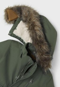 Giacca verde oliva con cappuccio foderato in pelliccia sintetica, caratterizzata da un accento in pelle marrone, tasche con zip e una morbida fodera interna.