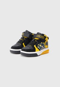 Sneaker a metà altezza nere e gialle con grafica di Batman, chiusura con strap in Velcro, tomaia testurizzata, suola in gomma e punta rotonda.