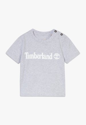 T-shirt manches courtes gris clair pour tout-petit avec logo Timberland et icône d'arbre en blanc, avec des boutons sur l'épaule gauche.