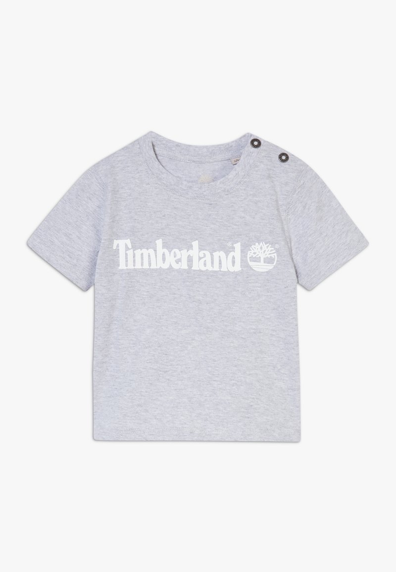 T-shirt manches courtes gris clair pour tout-petit avec logo Timberland et icône d'arbre en blanc, avec des boutons sur l'épaule gauche.