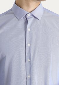 Camicia button-up a righe azzurro chiaro con colletto a punta, dotata di bottoni bianchi e una texture morbida e liscia.