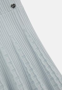 Jasnoniebieska dzianinowa spódnica o prążkowanej strukturze, z pionowymi wycięciami i małą czarną metką z logo.