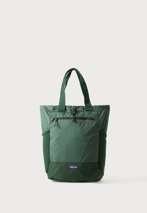 Grøn Patagonia tote taske med dobbelte håndtag, front lynlåslomme, sidelommer og et lille mærke nederst i midten.