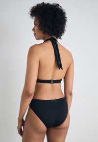 Sorte bikinitsett med halterneck-topp med knyting og matchende høy midje-bikiniunderdeler, glatt tekstur og minimalistisk design.
