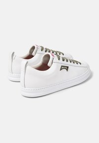 Scarpe da ginnastica in pelle bianca con lacci verde oliva, suola in gomma testurizzata e piccolo dettaglio con logo. Presentano cuciture decorative e linguetta posteriore.