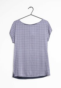 Blusa a maniche corte con motivo floreale geometrico blu e rosa appesa a un gancio nero su sfondo bianco.