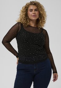 Sort langærmet top med gennemsigtige meshærmer og spredte sølvprikkede detaljer. Tilsiddende silhuet med rund halsudskæring.
