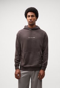 Donkerbruine hoodie met een voorzak, trekkoordkap, ribgebreide manchetten en zoom. Beschikt over het "Marc O'Polo DENIM" logo in het wit.