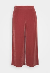 Pantalon à jambes larges en tissu rouille doux et texturé, taille haute avec plis à l'avant. Présente une coupe droite et nette, sans éléments métalliques visibles.