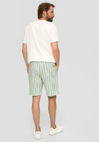 Helles T-Shirt kombiniert mit grün gestreiften Shorts aus leichtem Stoff, mit einer Gesäßtasche und einem lässigen Schnitt.