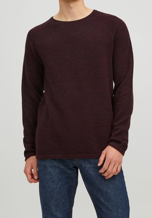 Bordeaux gebreide trui met lange mouwen, ronde hals en textuurstof. Geschaard met blauwe denim jeans, weergegeven op een model.