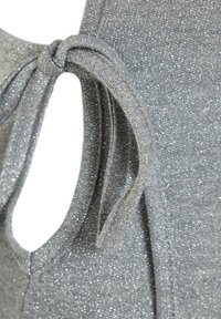 Gros plan sur un tissu argenté pailleté avec une découpe en forme de trou de serrure et un détail de nœud décoratif.