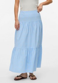 Blå och vit rutigt långkjol med lager av volang, elastisk midja och lätt tyg. Matchas med bruna flip-flops.