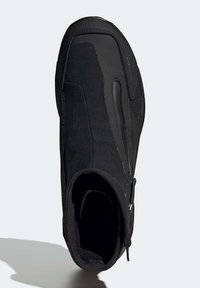 Bottine noire avec un dessus lisse et texturé, fermeture éclair et bout rond. Fabriquée en matériau durable, avec des lignes de design élégantes.