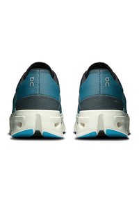 Des chaussures de course avec une tige turquoise, des accents gris et des semelles blanches. Le design présente un talon rembourré et des trous de ventilation pour la respirabilité.