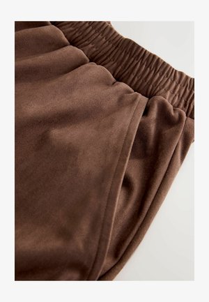 Braune Jogginghosen aus weichem Stoff mit elastischem Bund und unauffälliger Seitentasche, teilweise zu sehen.