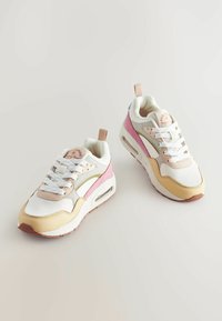 Des baskets avec une tige en maille blanche, des accents rose pastel et jaune, un col rembourré et une unité d'air visible dans la semelle.