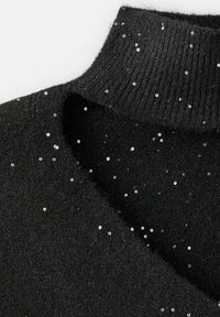 Svart ulltröja med ribbkrage och spridda silverpaljetter för extra textur. Närbild som framhäver tyget och dekorationerna.